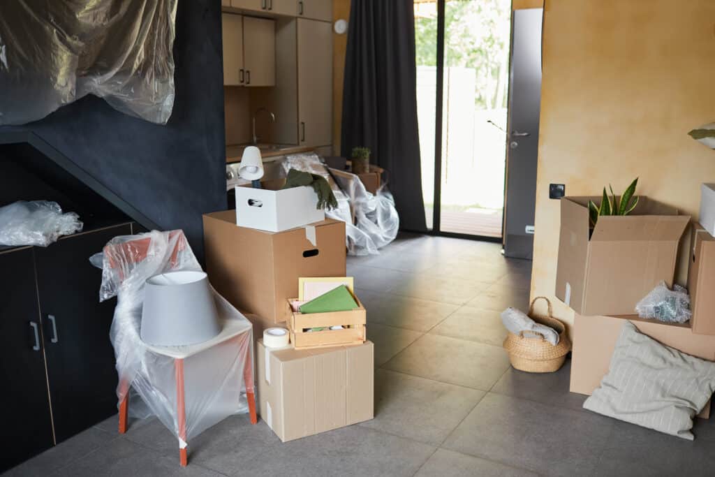 background image of messy cardboard boxes in new home family moving and relocation concept copy space